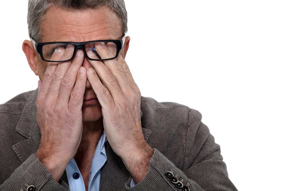 Man rubbing his eyes, beneath his glasses