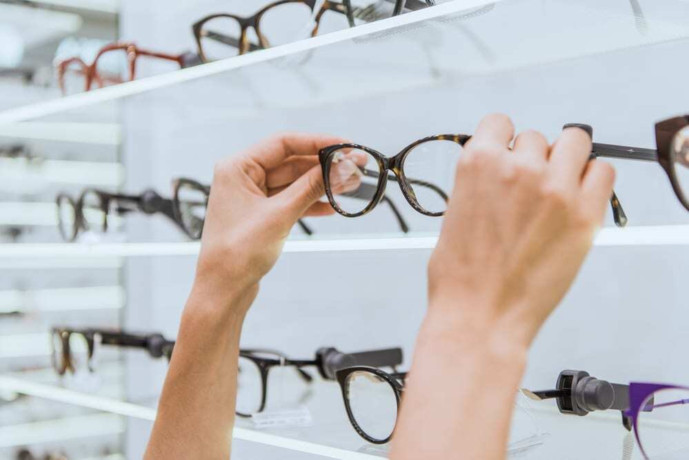 Hands reaching for glasses from selection at eyeglass store