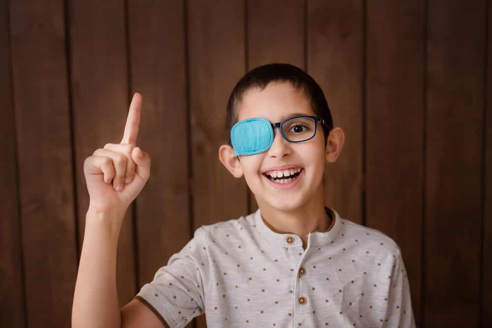 Smiling young boy with glasses patch treatment for lazy eye