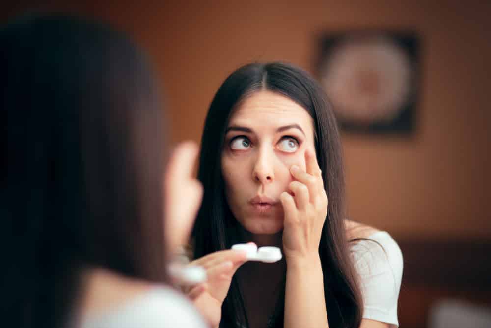 Young woman putting in contact lenses