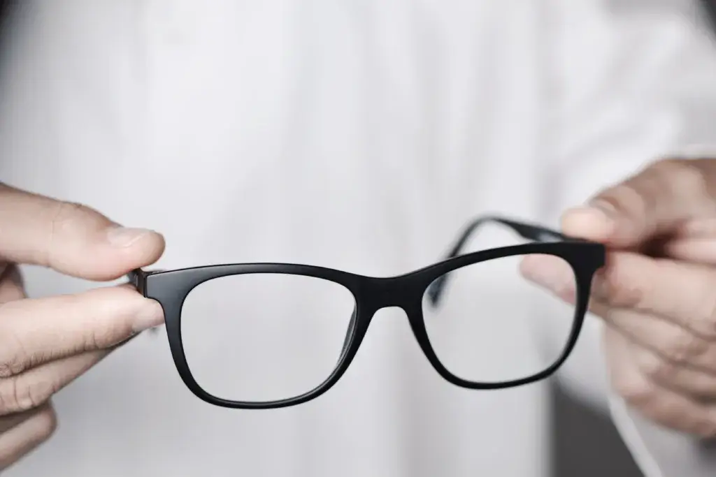 Hands holding a pair of glasses with black frames