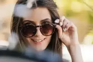 Portrait-of-young-woman-wearing-sunglasses-lifting-them-off-her-nose