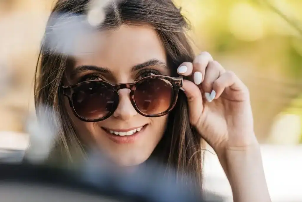 Portrait of young woman wearing sunglasses, lifting them off her nose