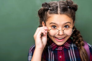 Portrait-of-schoolchild-looking-above-glasses-near-blackboard