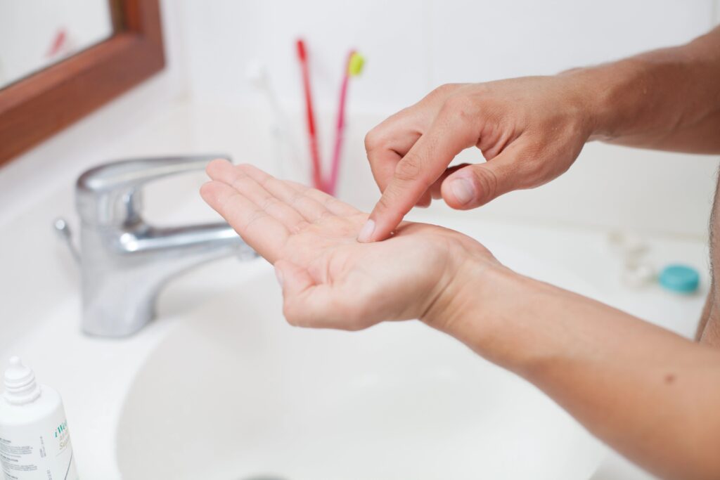 Close-up of person cleaning contact in palm of other hand