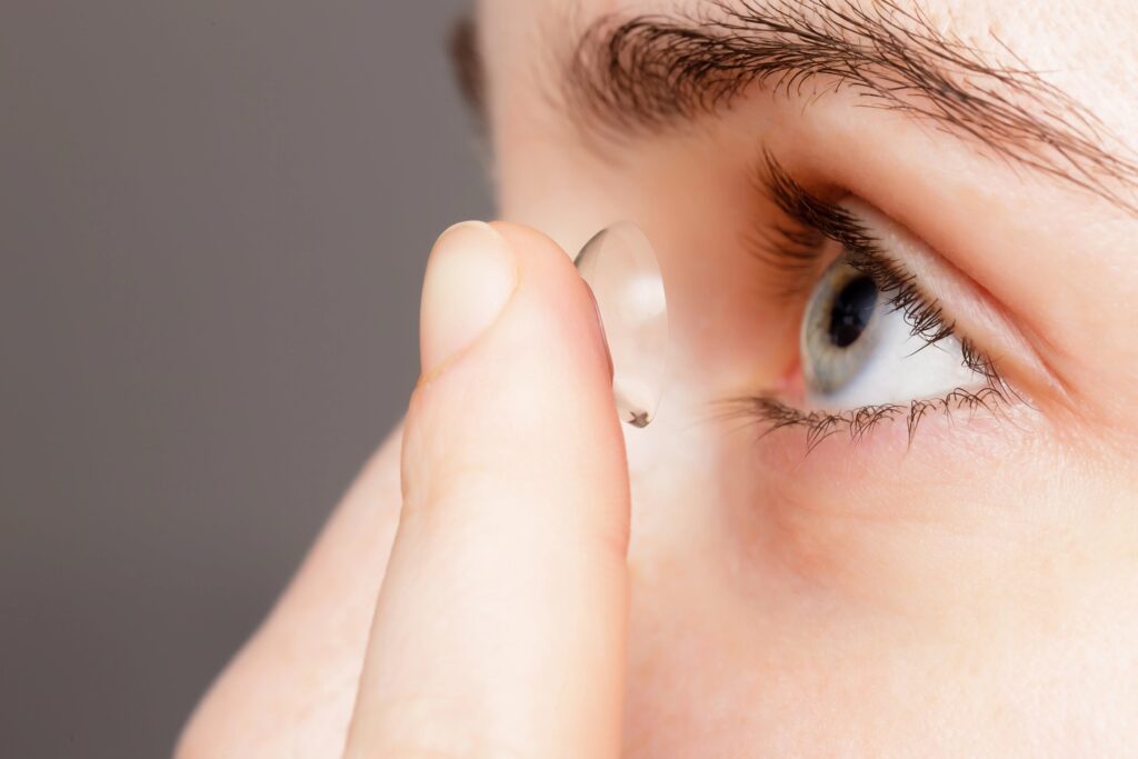 Close-up of young woman putting contact lens on eye