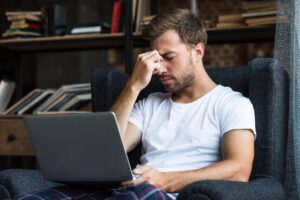 Man holding hand to his eyes, looking tired and uncomfortable