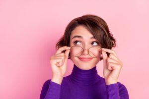 Young woman holding glasses on tip of nose