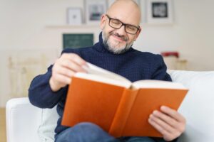 Older man reading book, wearing reading glasses
