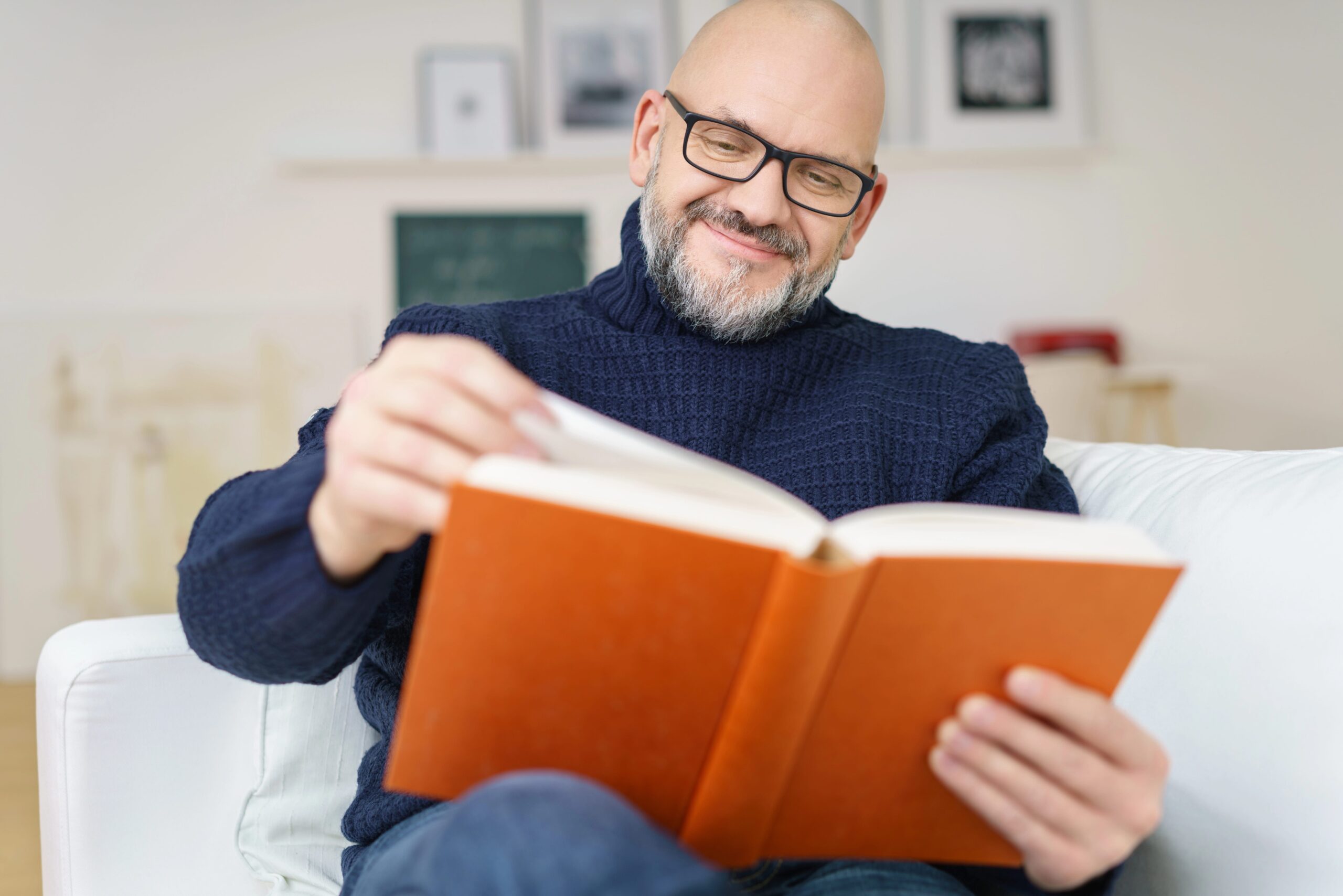 Older man reading book, wearing reading glasses