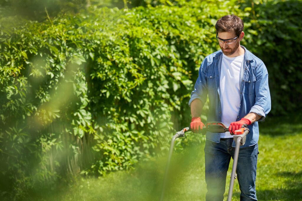 Man mowing lawn wearing safety glasses